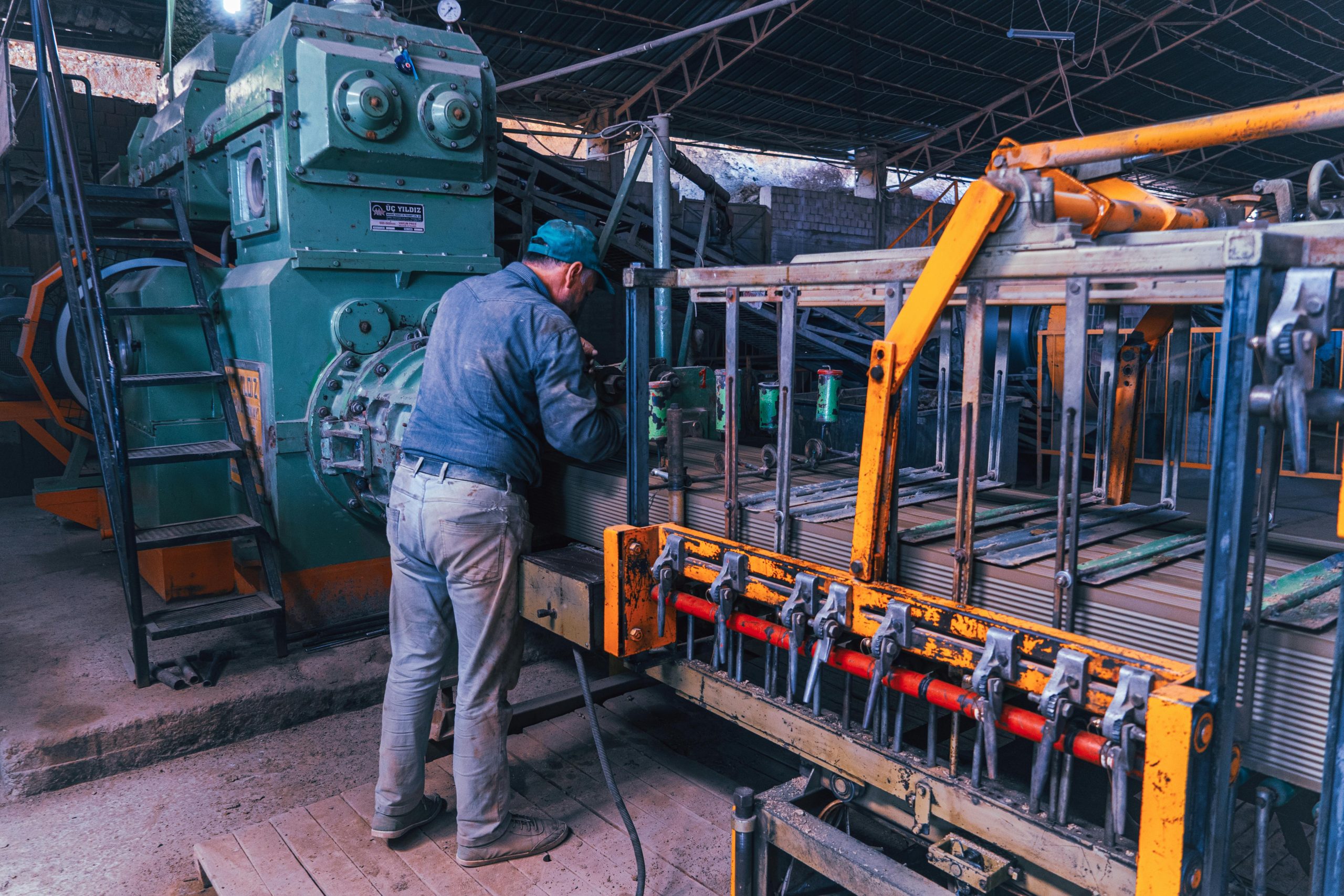 A factory worker operates heavy machinery in an industrial setting, depicting a typical manufacturing scene.