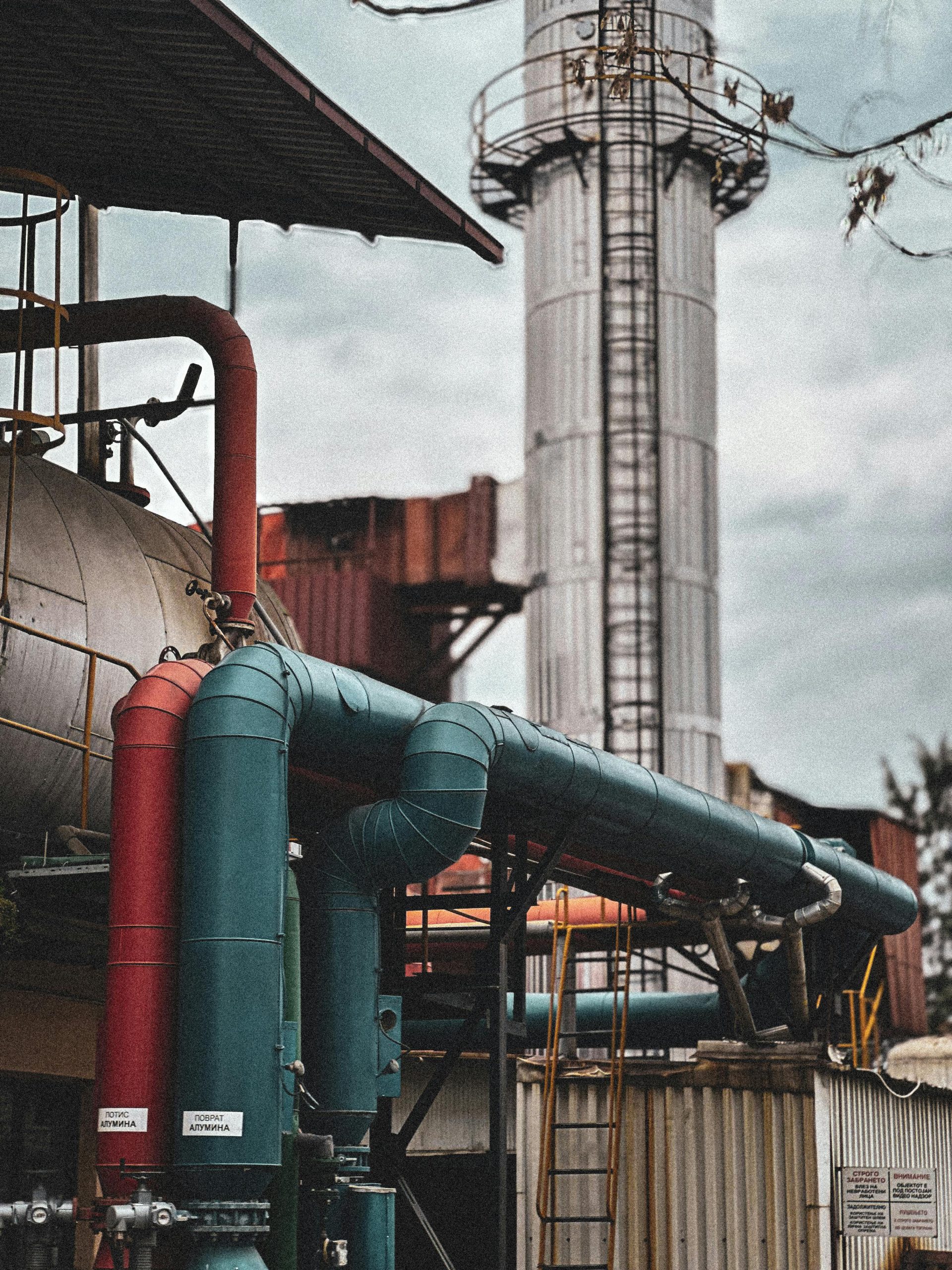 View of an industrial facility showcasing colorful pipes and structures under a cloudy sky.